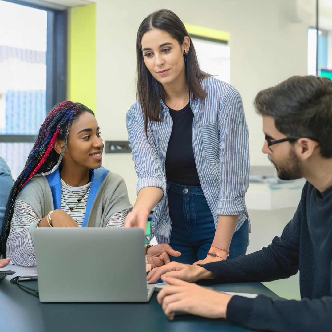 Three students working together around laptop.