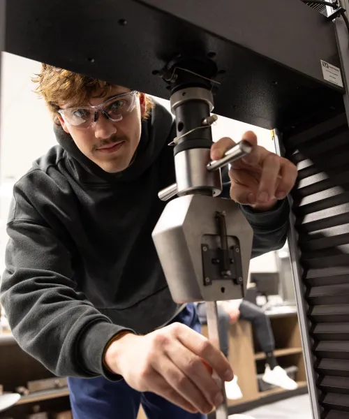 Young man working on engineering testing materials with large tension vice