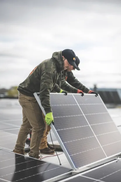 Two men installing solar panels on roof