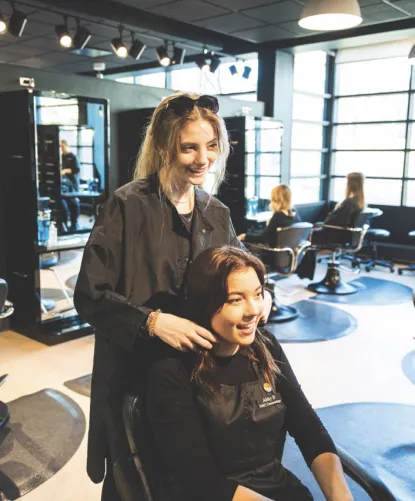 Young cosmetologist preparing to cut young customer's hair