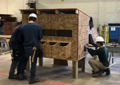 Students in hard hats working on chicken coop