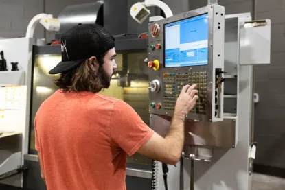 Young man programming a CNC machine in an industrial setting