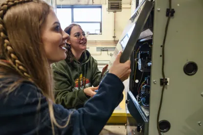 Two young women removing a panel from a furnace