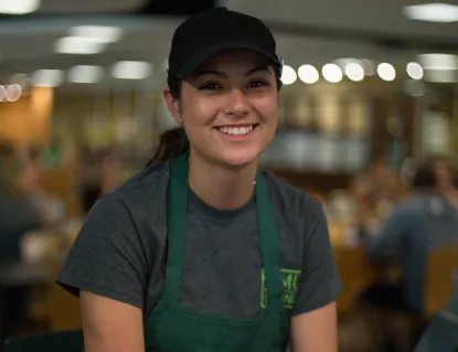Student dining employee smiling while on shift.