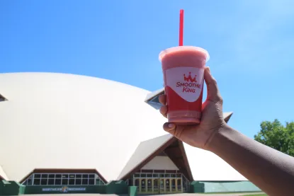 A Smoothie King smoothie being held in front of the Superior Dome