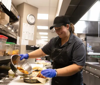 Student employee making wings at The Wildcat Den