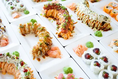 A variety of sushi rolls on white plates