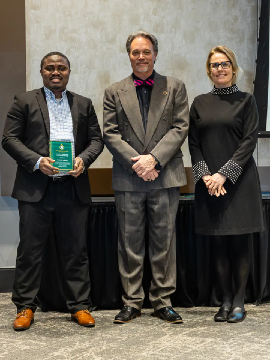 dr. jelili adebiyi receiving award, with president dr. chris olsen and provost dr. anne dahlman