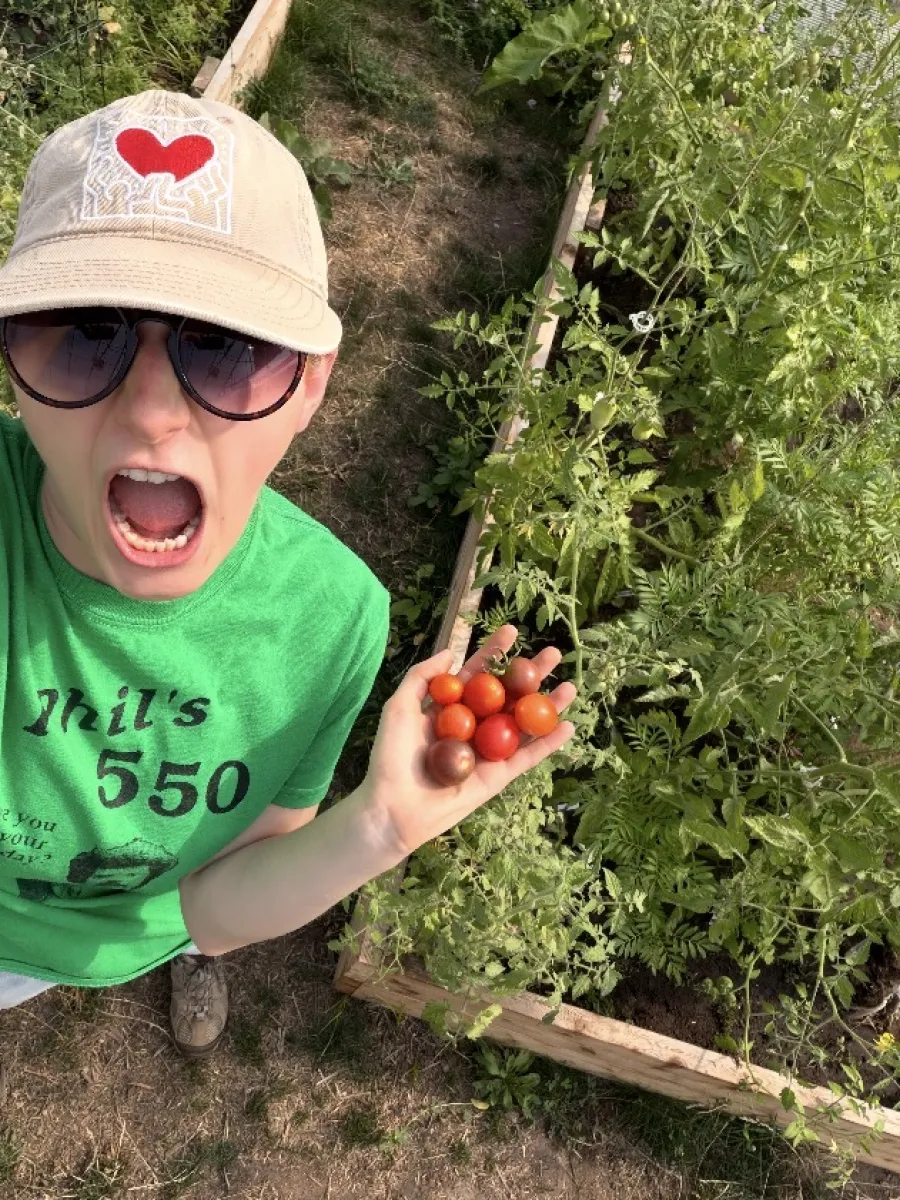 Carlee Sawvel taking a selfie with tomatoes harvested from the Hoop House