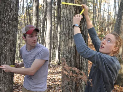 Connor O'Loughlin and Ally West measuring in Dead River Community Forest