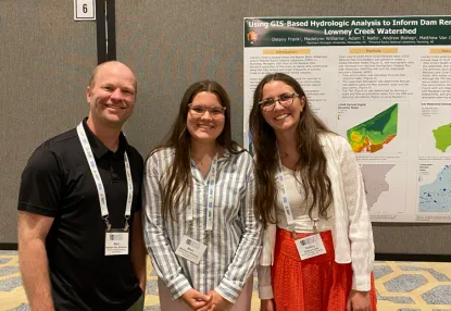 Dr. VG, Madelynn, and Delany standing in front of a poster