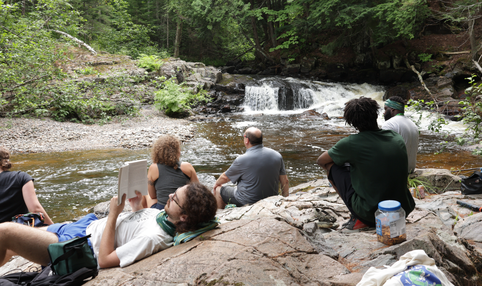 People relaxing by the Yellow Dog River in Big Bay during the PIPOC Outdoors Rest Retreat