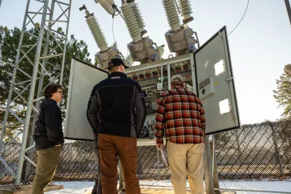 three males working an outdoor electrical box