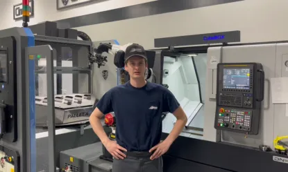 MET graduate standing in front of his machining workstation.
