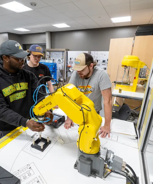 Students working at a Fanuc Robotic workstation located in the NMU Jacobetti Complex.