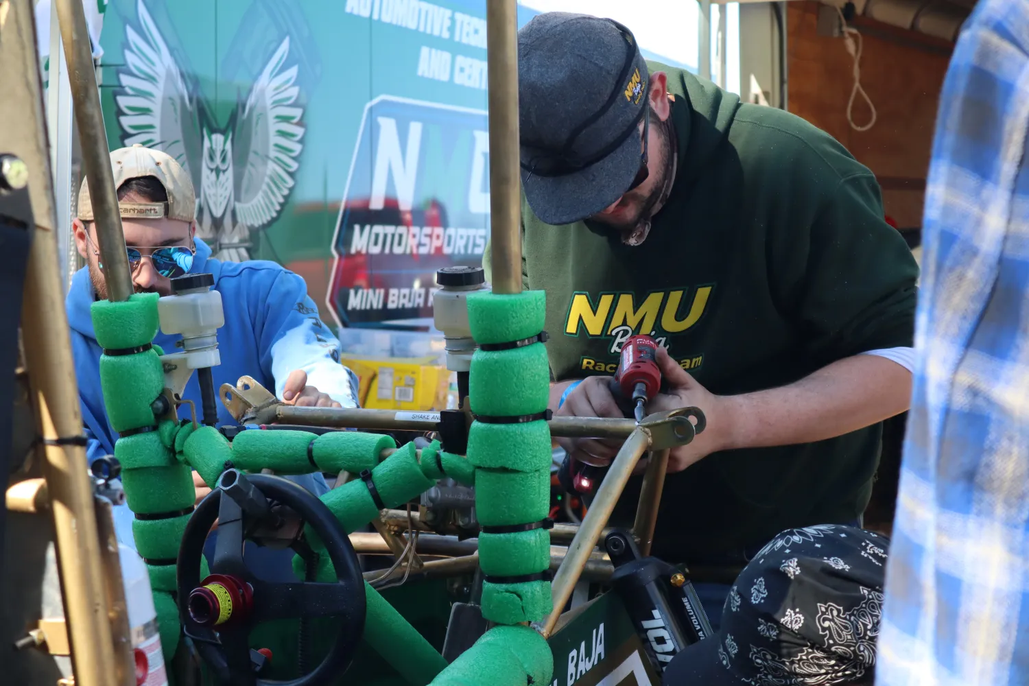 Two team members are making some adjustments to the rear of the vehicle during the Backwoods Race.