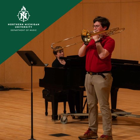 Northern Michigan University music performance: a trombonist in red plays onstage while a pianist accompanies him at a grand piano.