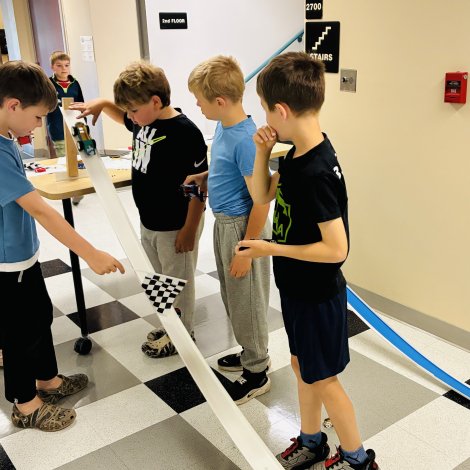 young students racing a glow-cut forge printed car they designed down a ramp