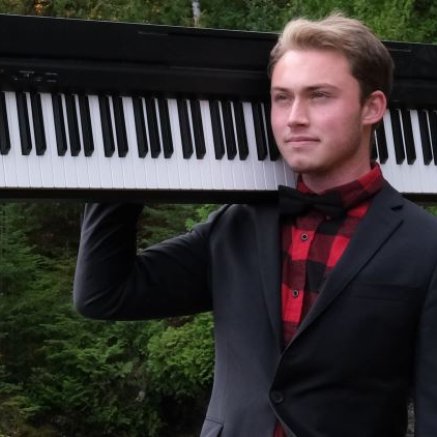 man in flannel and suit jacket holding a keyboard on his shoulder in the woods