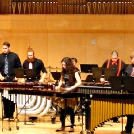 people playing marimbas and xylophones on a stage