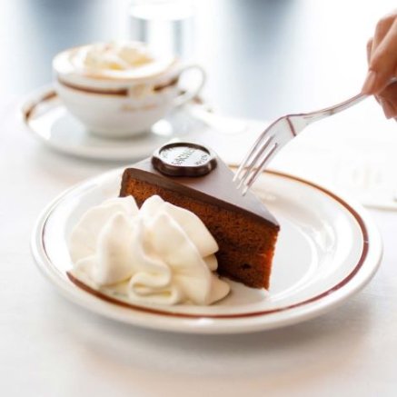 chocolate cake on a white plate next to a cup of coffee
