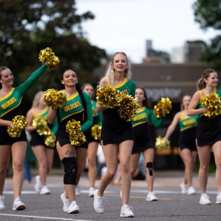 NMU cheerleaders walking in a parade on the street 