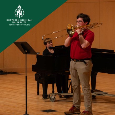Northern Michigan University music performance: a trombonist in red plays onstage while a pianist accompanies him at a grand piano.