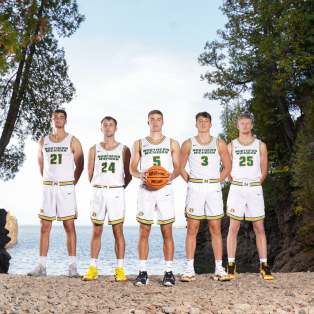 five male basketball players standing on the shore of Lake Superior