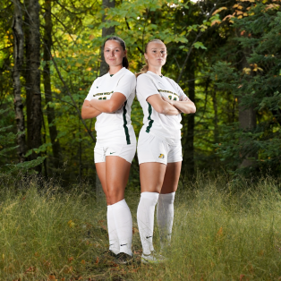two female soccer players standing in the woods