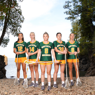 5 female lacrosse players standing on a beach