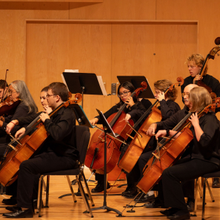 Close up on lower strings section of the Fall '24 University Orchestra playing on RRH stage