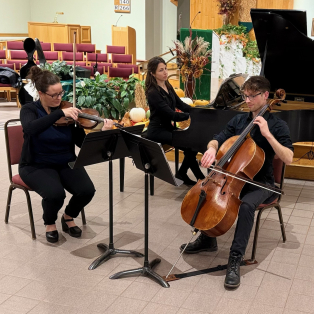 Dr. Theresa Camilli, Adam Hall, and Danielle Simandl in all black, performing in a lobby space