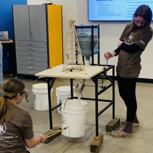 student testing the amount of sand their tower will hold