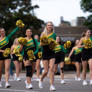 NMU cheerleaders walking in a parade on the street 