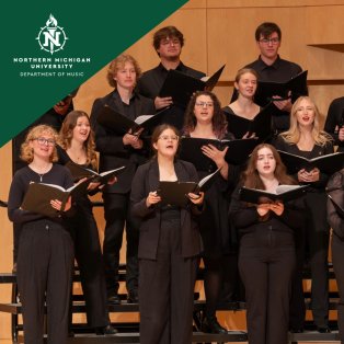 Northern Michigan University choir performs in black attire, holding music folders on risers against a warm wood backdrop; focused, joyful expressions.