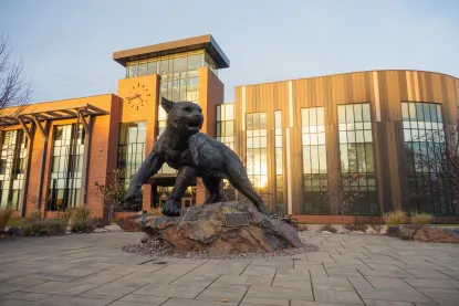 NMU Wildcat Statue in front of Jamrich building at golden hour