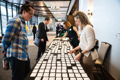 a woman and a man talking while looking at a table filled with name tags 