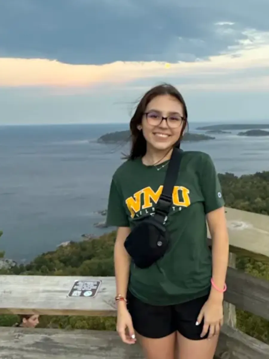 Girl standing on top of a mountain with the view of a large lake behind her