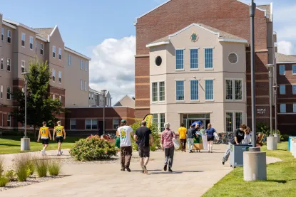 Students are outside, walking up to the entrance of Maple West