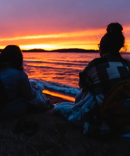 Two students watching a sunset over Lake Superior