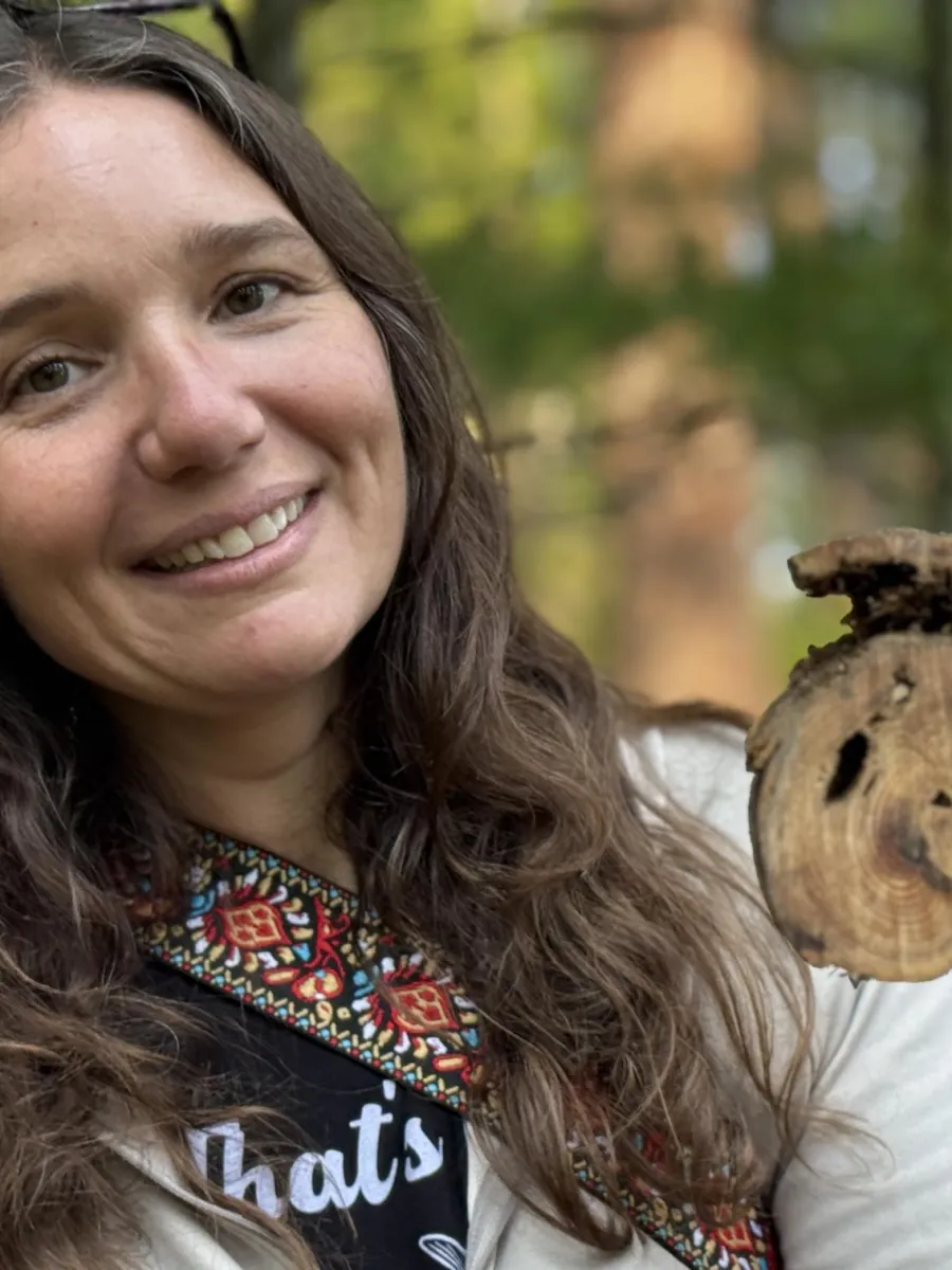 Lori Gambardella is smiling in an outdoor setting holding medicine