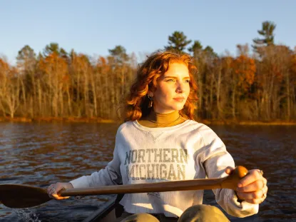 Woman in a canoe wearing a Northern Michigan sweatshirt