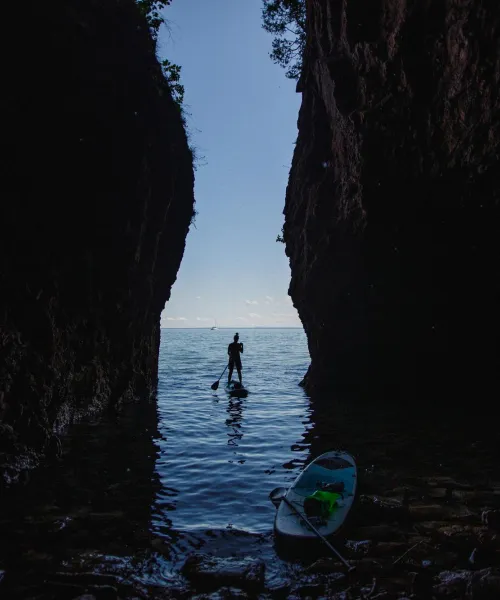 Student paddle boarding through a cove