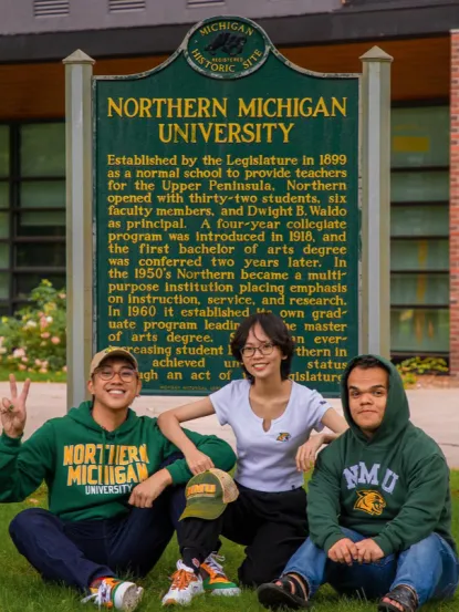 Three international students in front of NMU Sign 