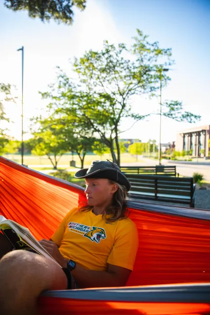 Student reading in hammock in academic mall