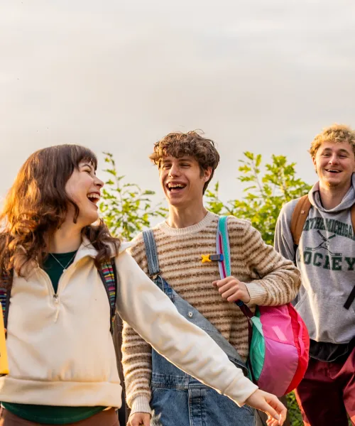 Three students walking in a line and laughing