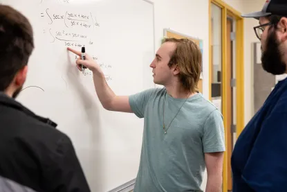 Student working on math problem on whiteboard