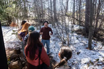 Man telling a story outdoors in winter with a group surrounding him, listening