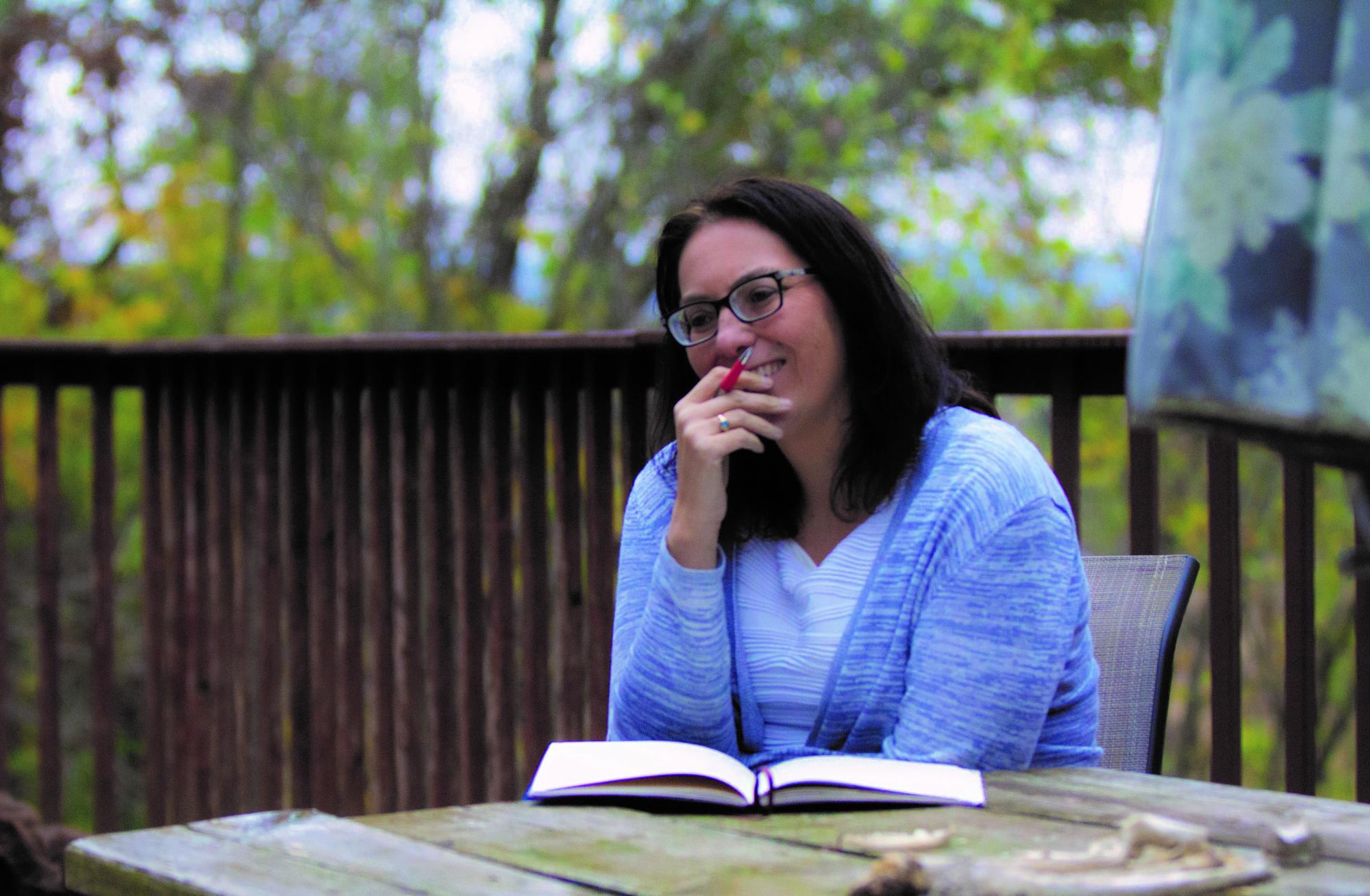 Beth Rondeau Deacon sitting outside with a notebook