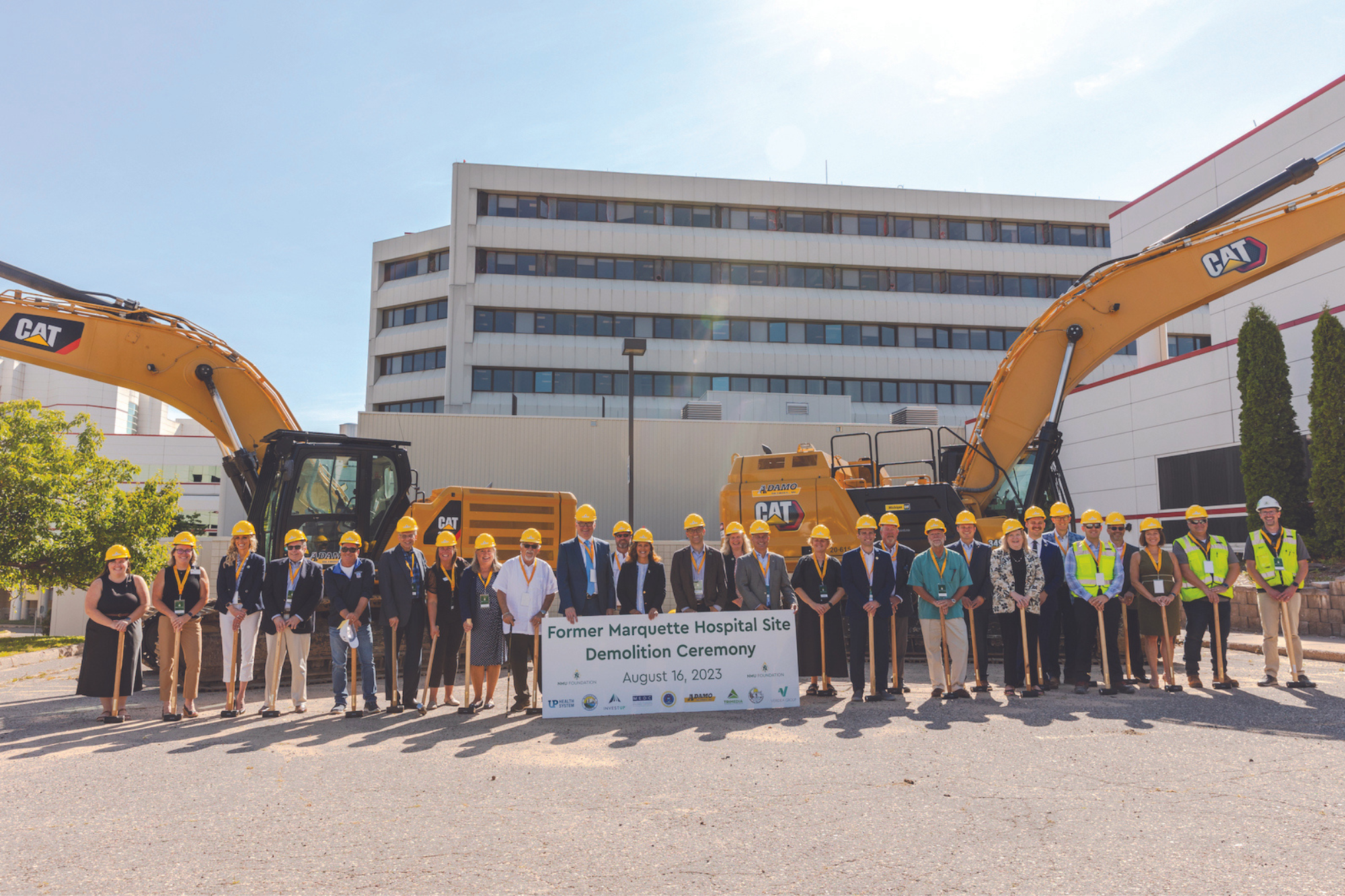 People stand in front of a building with construction equipment 